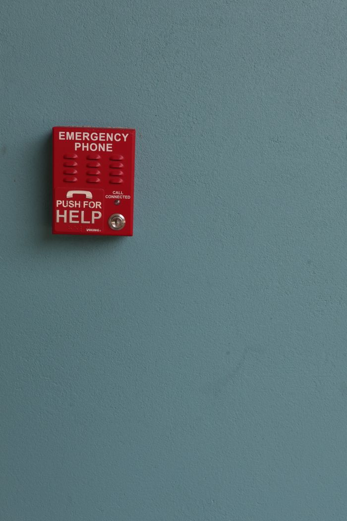 gallery-01 Red emergency phone mounted on a blue wall, offering help with a simple push.
