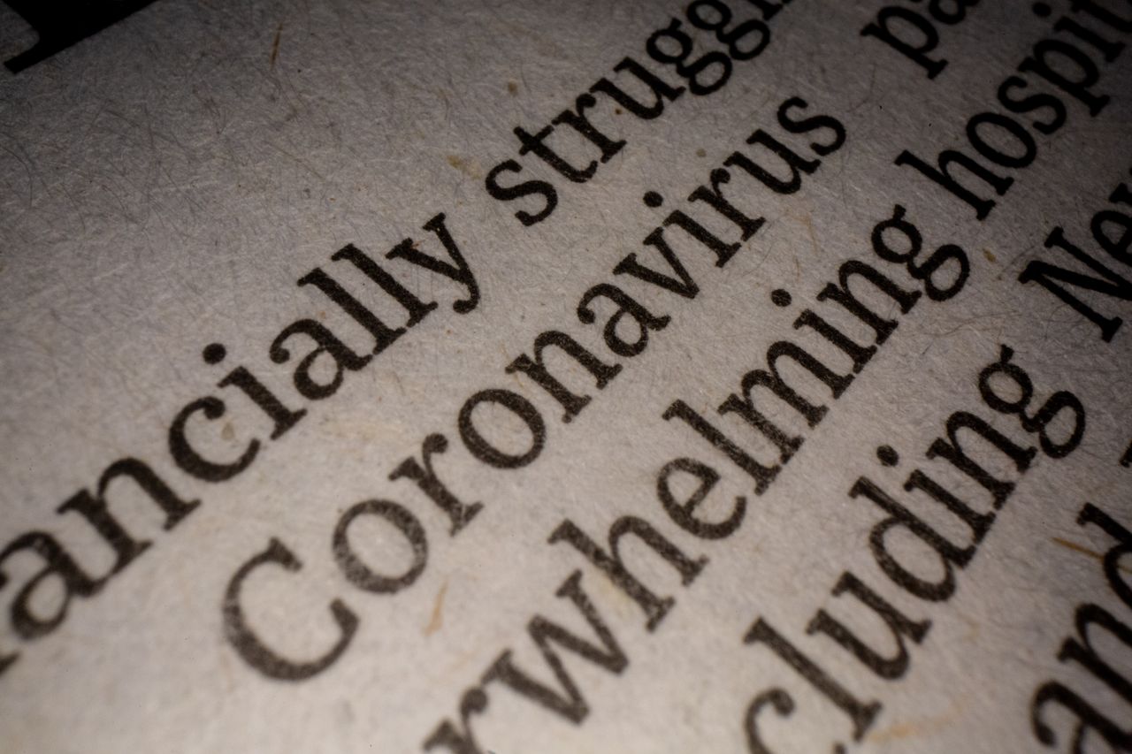 about-img-01 Closeup white page of article with black font about coronavirus pandemic research and economy impact